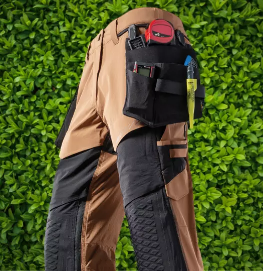 Nahaufnahme einer Arbeitshose in Blau und Schwarz mit mehreren seitlichen Werkzeugtaschen